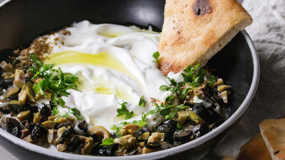 Labneh - Strained Yogurt served in a bowl and garnished with chopped olives