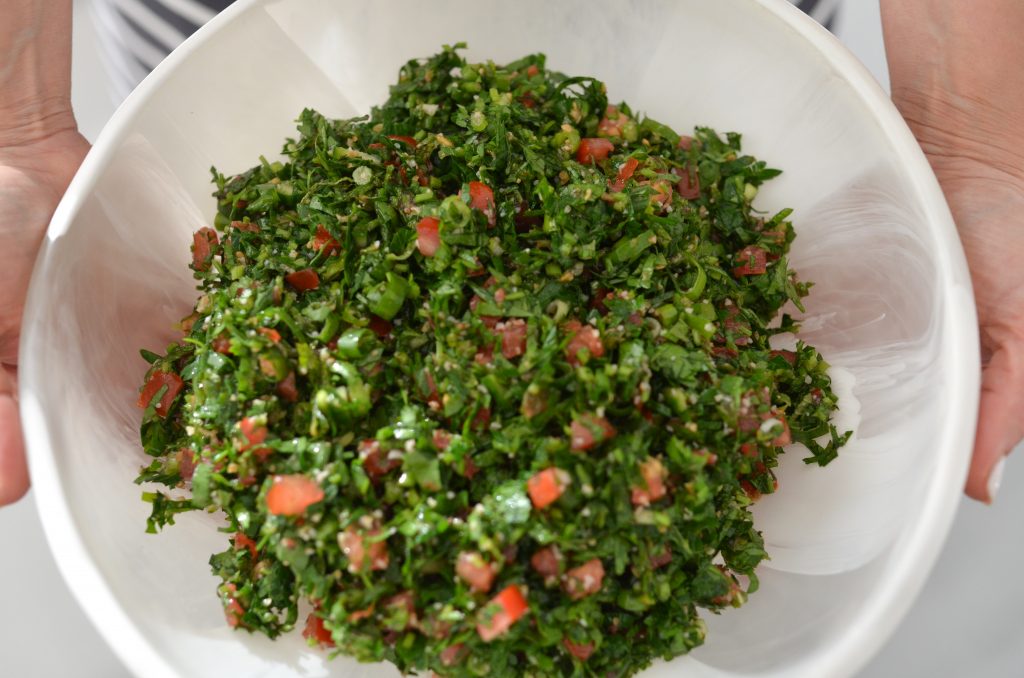 tabouli salad in a white dinosaur design bowl held by rouba shahin