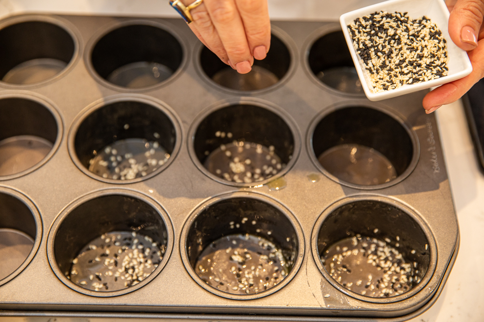 sprinkling sesame seeds in muffin tray