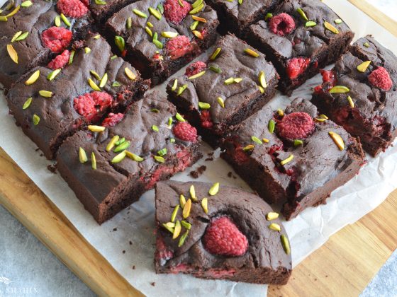 raspberries and pistachio brownies served on a board